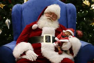 Dressed as Santa Claus, Mark Tate pretends to sleep as he poses for photos with 4-week-old Leilani Mejico at a mall in Cerritos, Calif. on Tuesday, Dec. 17, 2013. (AP Photo/Jae C. Hong)